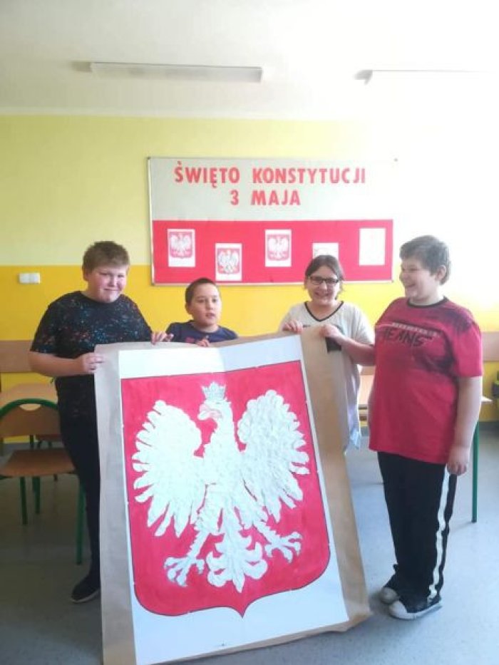Wychowankowie świetlicy prezentują swoją pracę plastyczną duże godło Polski.