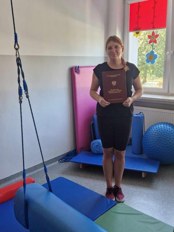 Pani Paulina pozuje do zdjęcia z dyplomem do nauczania gimnastyki korekcyjnej.