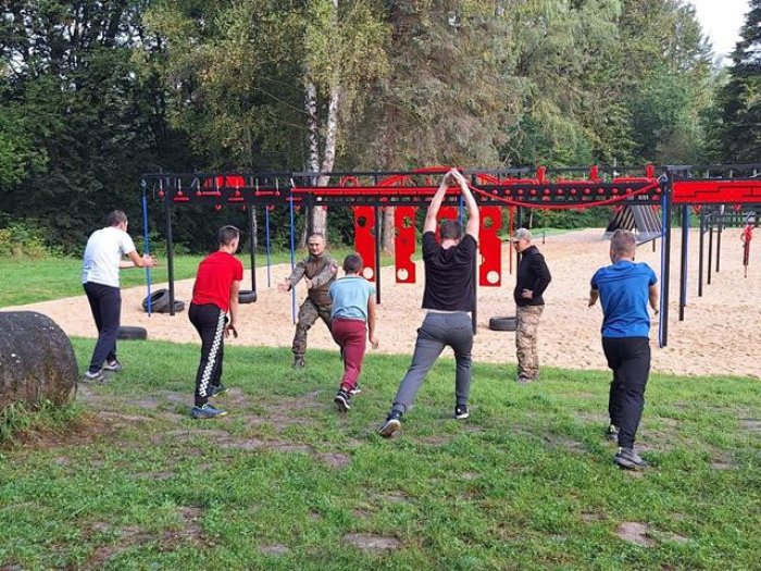 Uczniowie pod okiem trenera wykonują rozgrzewkę.