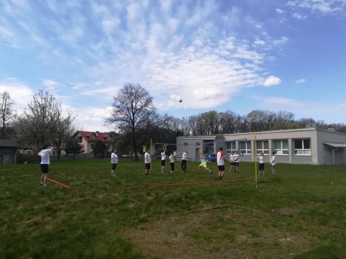 Uczniowie rozgrywają mecz siatkarski na szkolnym boisku. 