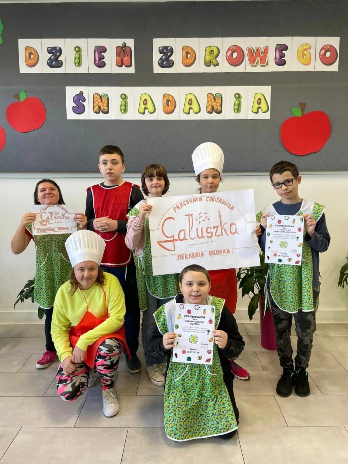 Uczniowie prezentujący  logo sponsora zdrowego śniadania,