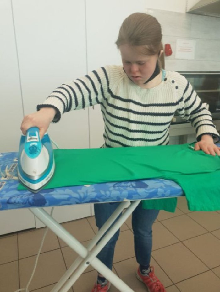 Uczennica obsługuje żelazko, stosując się do zasad bhp.