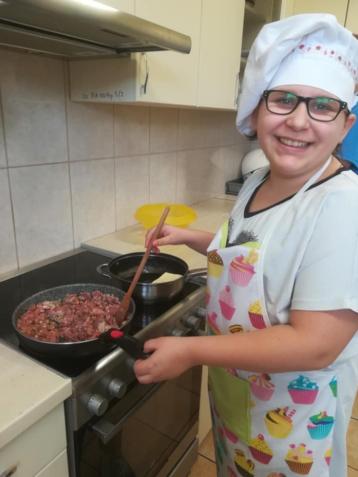 Uczennica smaży mięso mielone na patelni.