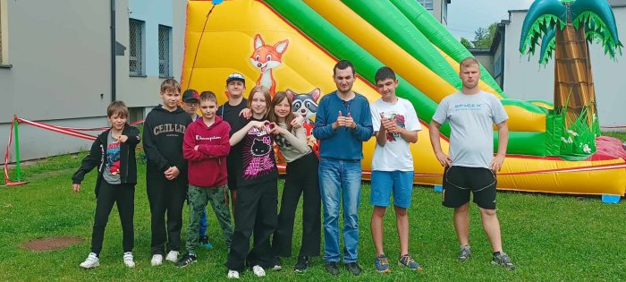 Uczniowie szkoły branżowej pozują na tle dmuchanej zjeżdżalni.