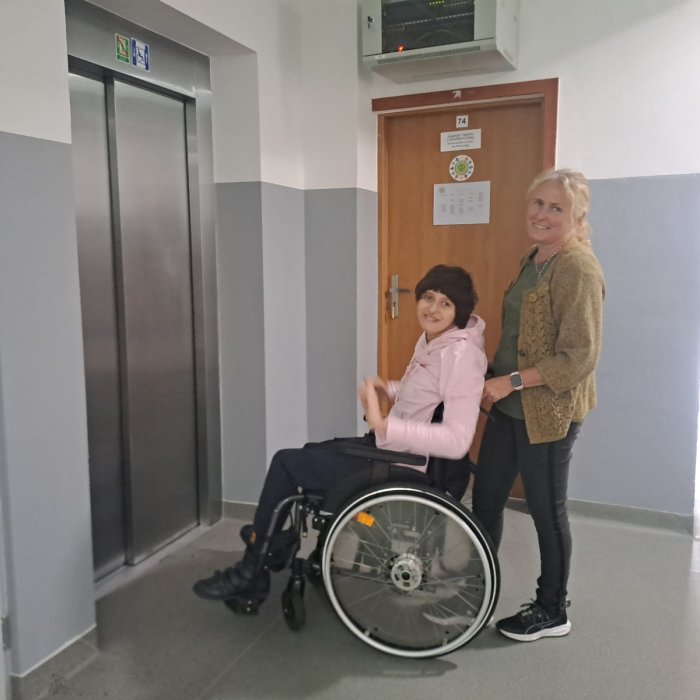 Uczennica niepełnosprawna pod opieką nauczycielki korzysta z windy.