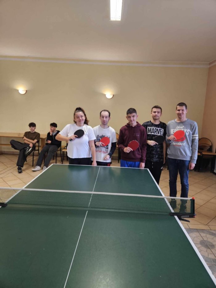 Ekipa tenisa stołowego wraz z trenerem panem Adamem na zawodach sportowych.