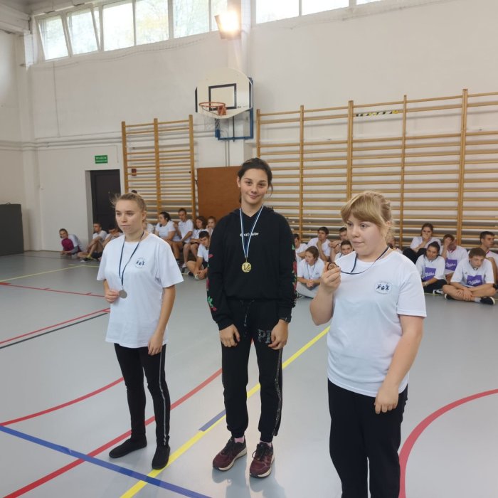 Uczennica prezentuje złoty medal  zdobyty w zawodach lekkoatletycznych.