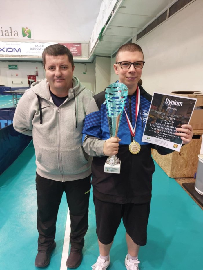 Uczeń wraz z trenerem prezentuje dyplom i puchar zdobyty za 1 miejsce.