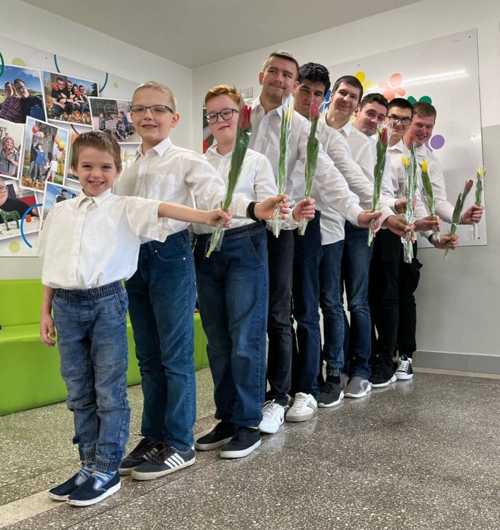 Chłopcy ubrani  odświętnie trzymają w swoich rękach tulipany.