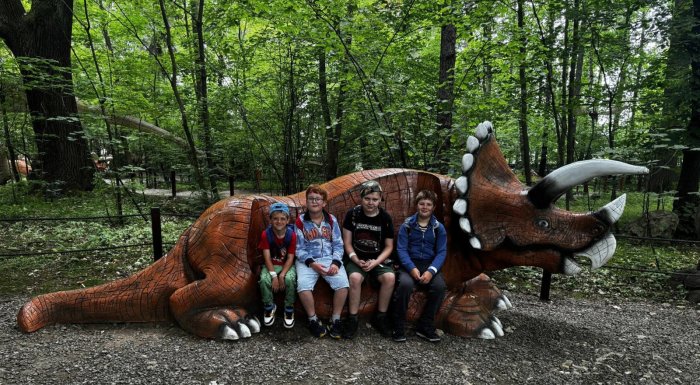 Uczniowie w parku ruchomych dinozaurów.