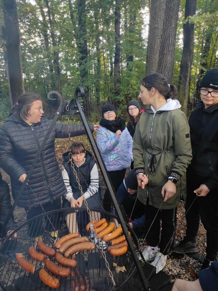 Uczniowie pieką kiełbaski.