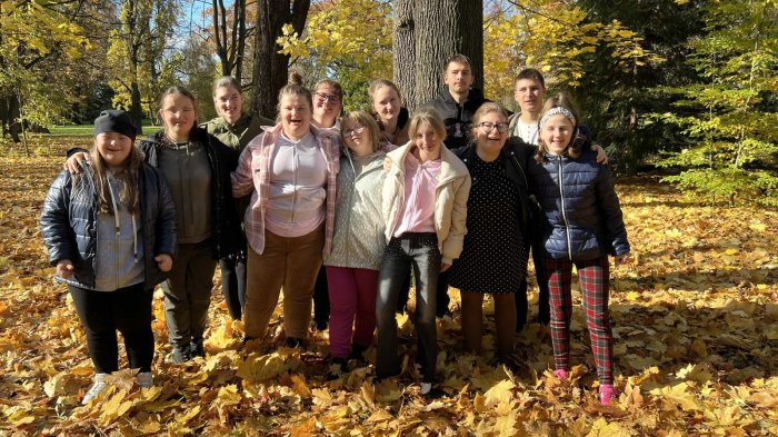 Uczniowie pozują do zdjęcia na tle jesiennego parku.