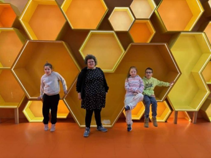 Uczniowie pozują do zdjęcia przy plastrach miodu.