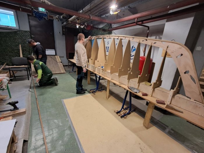 Uczeń czyści papierem ściernym kadłub łodzi.