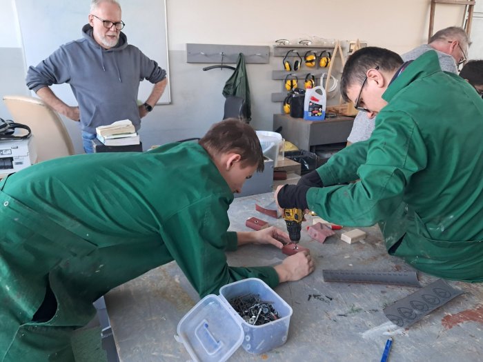 Uczniowie klas przysposabiających              do pracy pod okiem nauczyciela skręcają elementy łodzi.