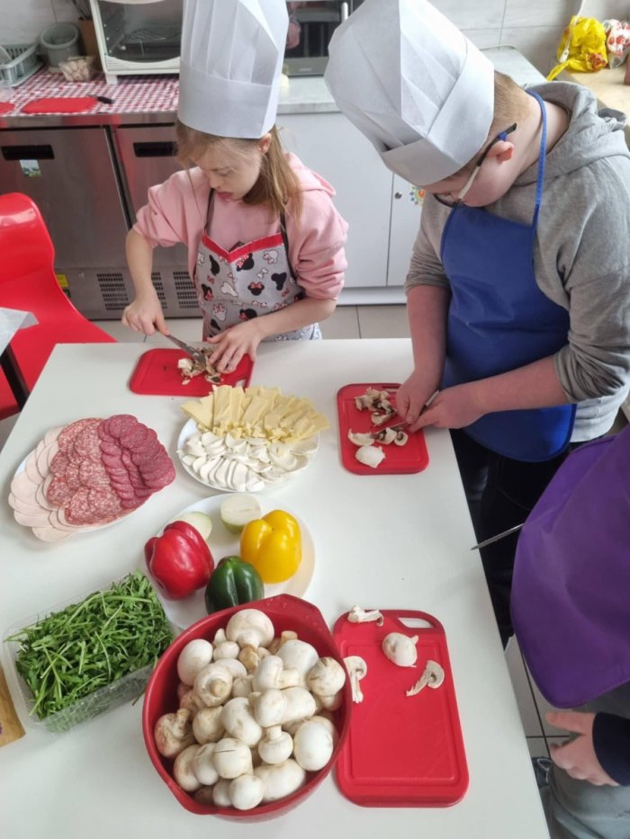 Uczniowie przygotowują składniki na pizze.