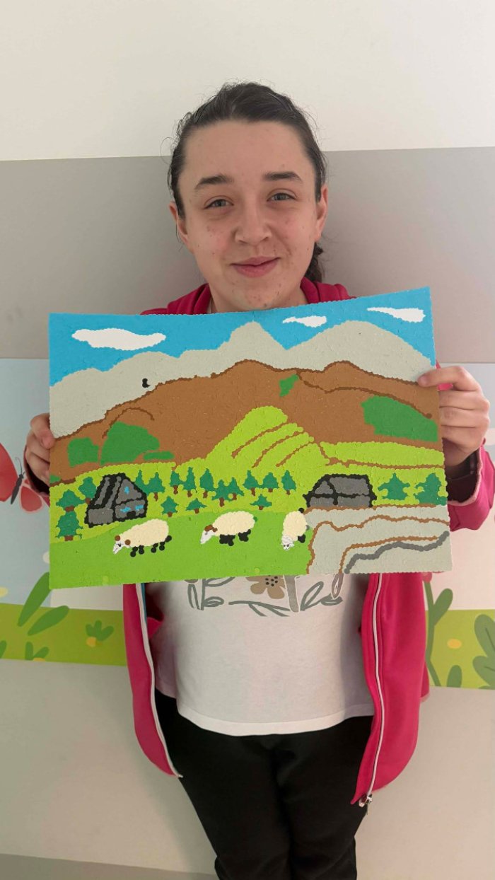 Uczennica prezentuje własnoręcznie wykonaną pracę plastyczną.