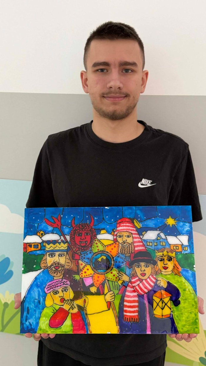 Uczeń prezentuje swoją pracę plastyczną wykonana techniką malowania na szkle.