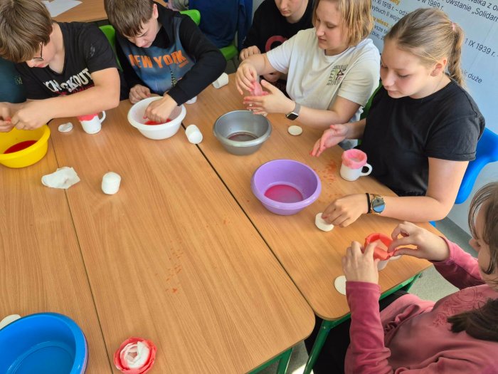 Uczniowie wykonują różyczki z papieru.