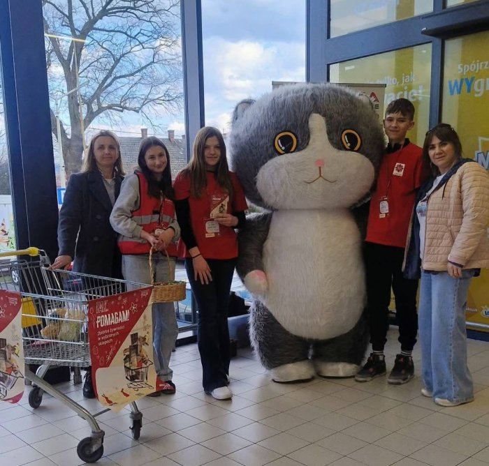 Wolontariusze z maskotką kota zbierają dary żywnościowe.