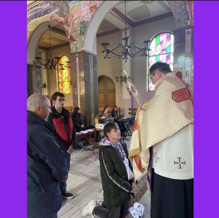 Uczeń klęka przed monstrancją.