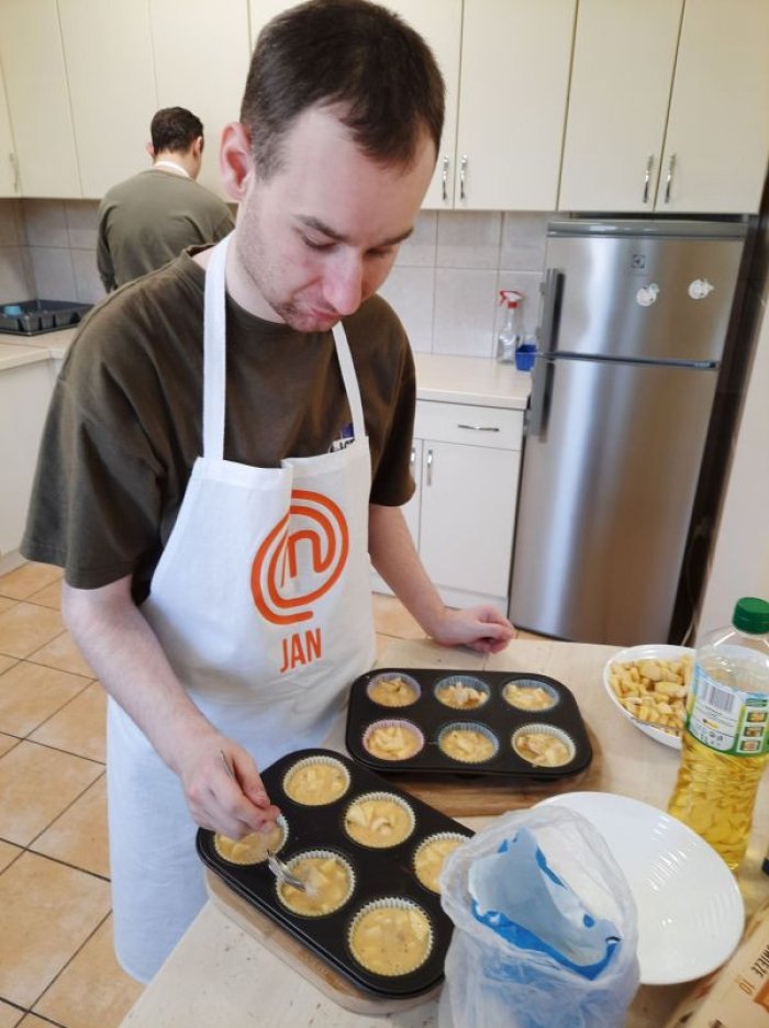 Uczeń wypełnia ciastem formę na muffinki 