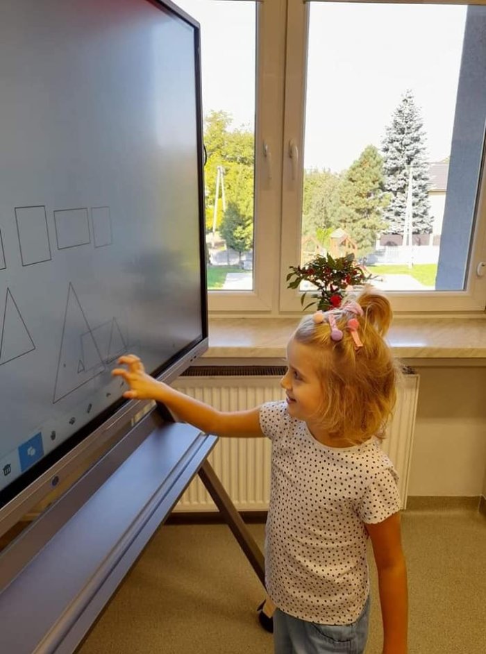 Uczennica wykonuje zadania na tablicy multimedialnej. 