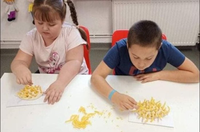 Uczniowie wykonują pracę plastyczną z makaronu pt: 