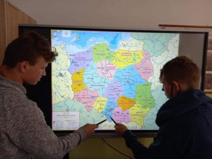 Uczniowie wskazują województwa na mapie Polski na telewizorze multimedialnym.