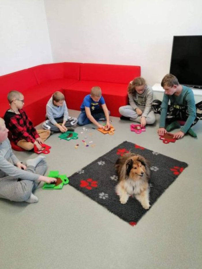 Uczniowie klas młodszych pozują do zdjęcia z Kerrią - psem terapeutycznym.