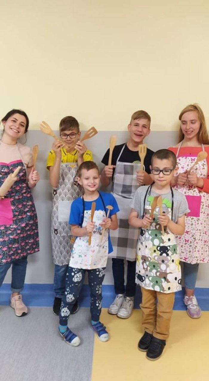 Uczniowie wraz z nauczycielem ubrani w nowe fartuszki kuchenne, zakupione na aukcji.