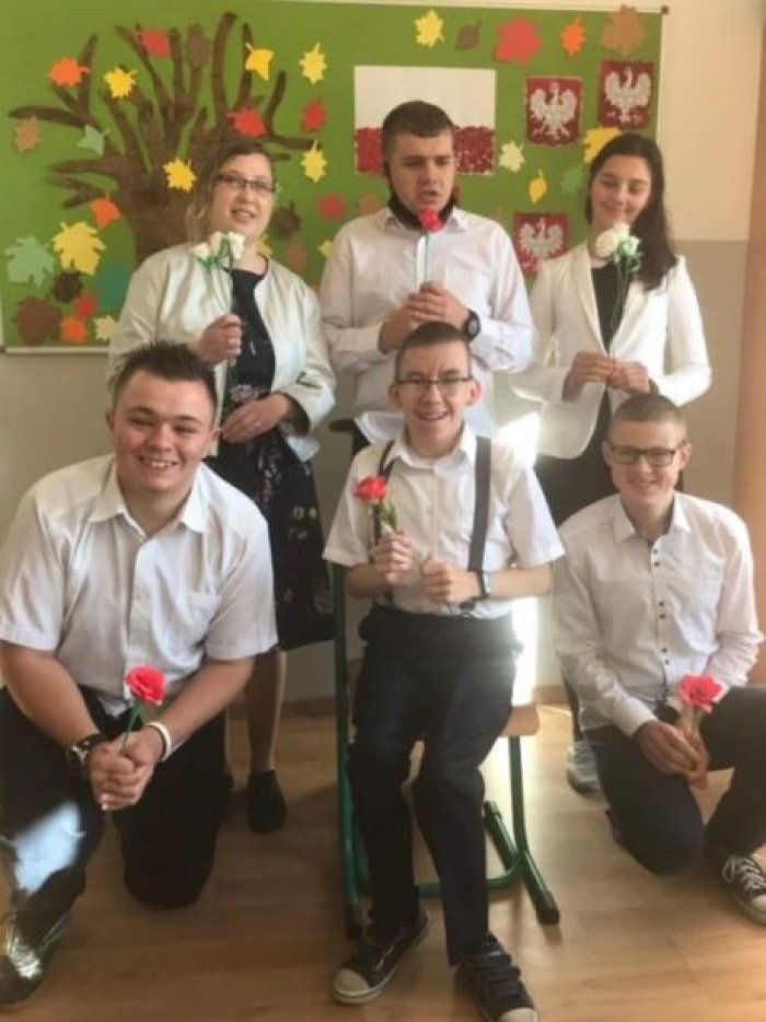 Uczniowie klasy III Pb ubrani w strój galowy z kwiatami w ręku świętują 11 listopada.