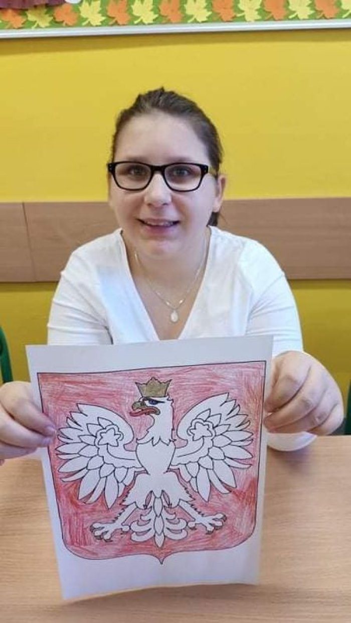 Uczennica prezentuje pracę plastyczną godło Polski.
