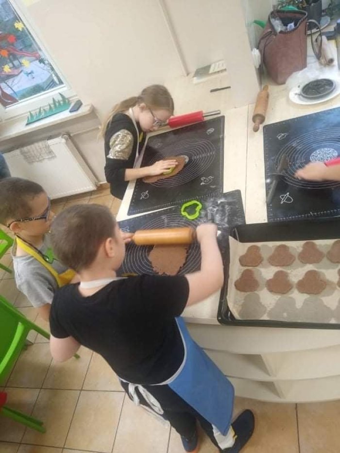 Uczniowie wałkują ciasto na pierniczkowe aniołki. 