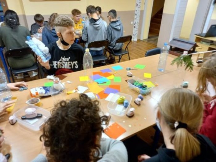 Uczniowie wykonują karmnik z plastikowej butelki.