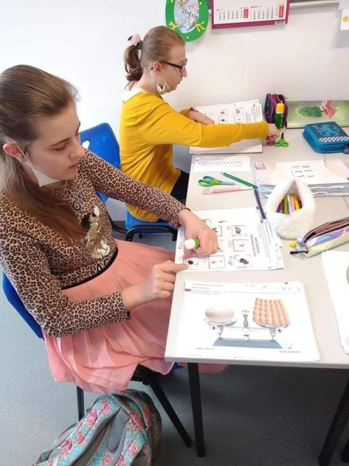 Uczennice wykonują zadania na kartach pracy.