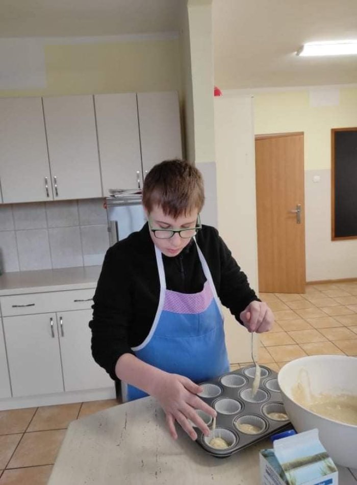 Uczeń  rozdziela masę na  babeczki. 