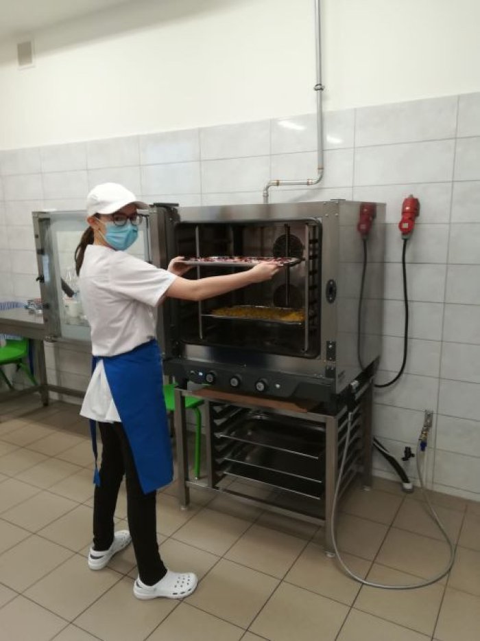 Uczennica obsługuje piec konwekcyjny w ramach zajęć praktycznych w kuchni.