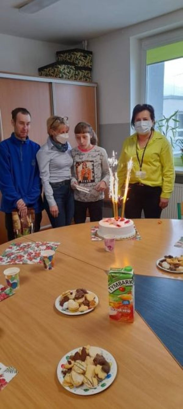 Solenizantka pozuje do zdjęcia z Paniami dyrektorkami i kolegami z klasy.