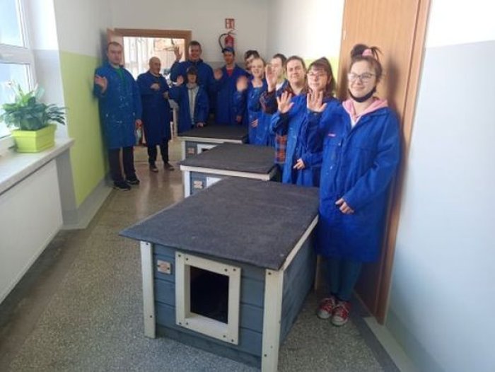Uczniowie prezentują drewnianą budę wykonaną w pracowni stolarskiej.