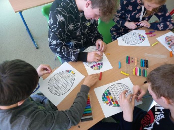 Uczniowie wylepiają plasteliną kontury wielkanocnych pisanek.