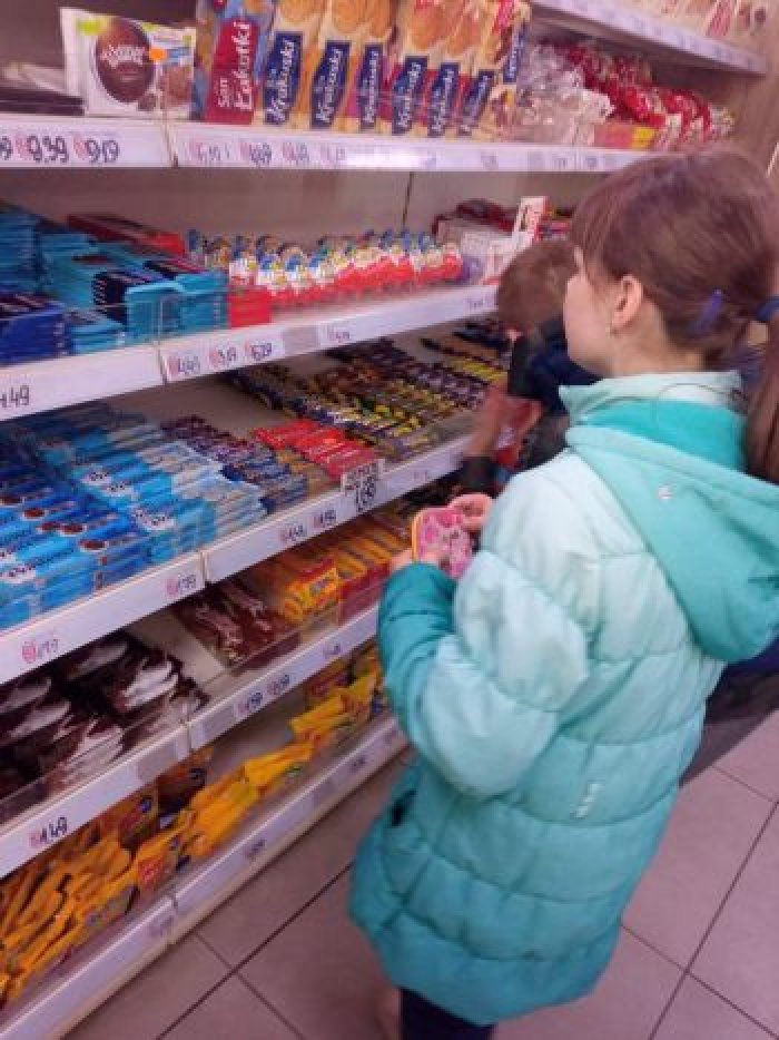 Uczennica wybiera produkty spożywcze w sklepie.
