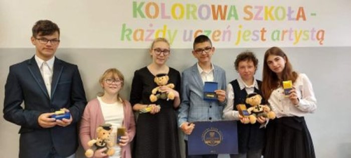 Uczniowie pozują do zdjęcia z upominkami otrzymanymi od Złotych Szkół Narodowego Banku Polskiego.