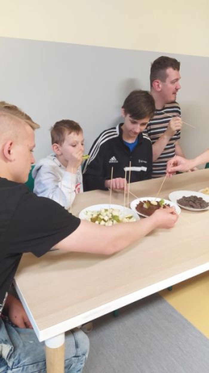 Uczniwoie degustują owoce w czekoladzie.