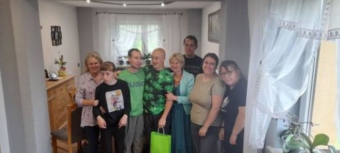 Absolwent pozuje do zdjęcia z Panią dyrektor, wychowawczynią, koleżankami i kolegami z klasy.