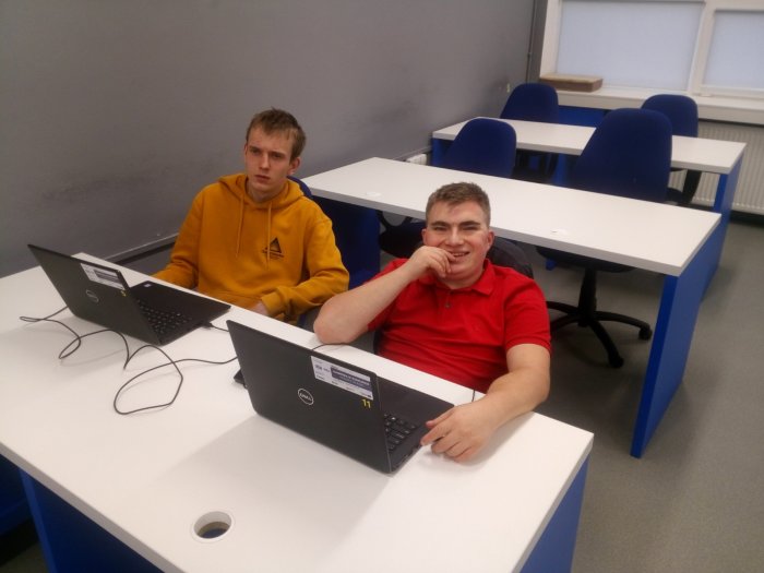 Uczestnicy siedzą w pracowni informatycznej przy laptopach.