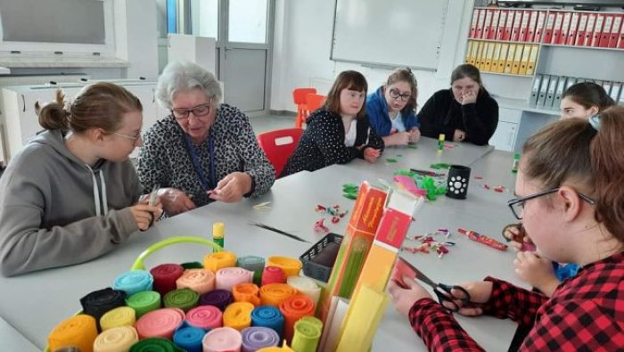 Uczniowie wykonują kwiatki z bibuły i krepiny.