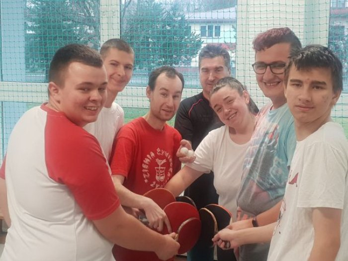Ekipa uczniów trenująca tenisa stołowego wraz z trenerem Adamem Juraszem. 