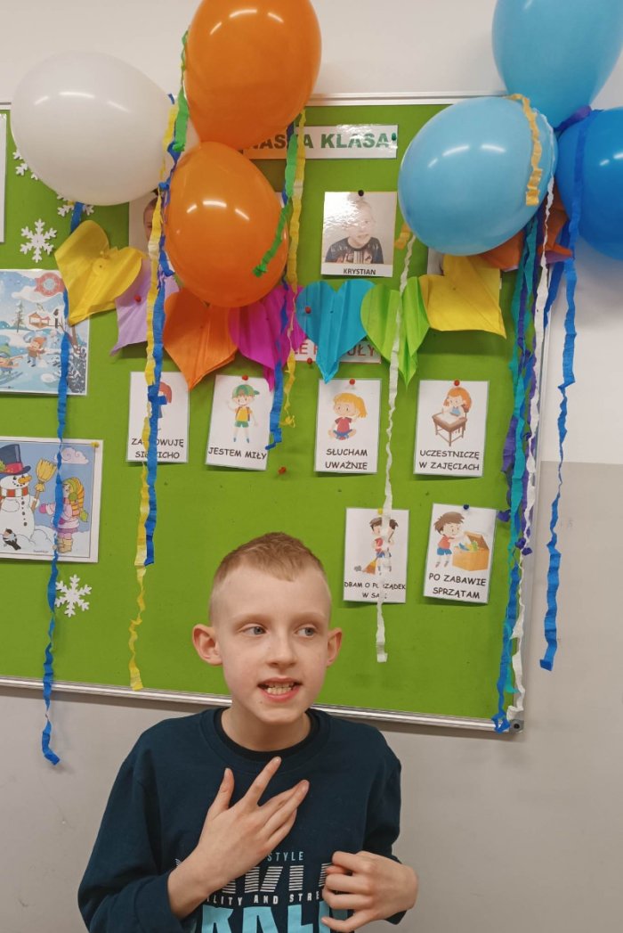 Solenizant Krystian pozuje do zdjęcia na tle dekoracji urodzinowej.