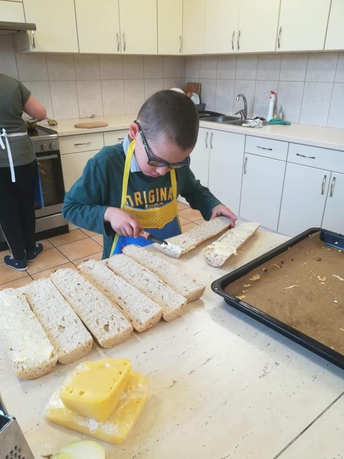 Uczeń smaruje bagietkę masłem. 